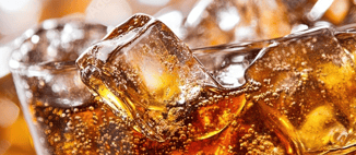 Close-up of ice cubes in a fizzy, brown soft drink, with visible bubbles rising to the surface