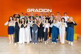Group photo of the Gradion team standing in front of an orange wall