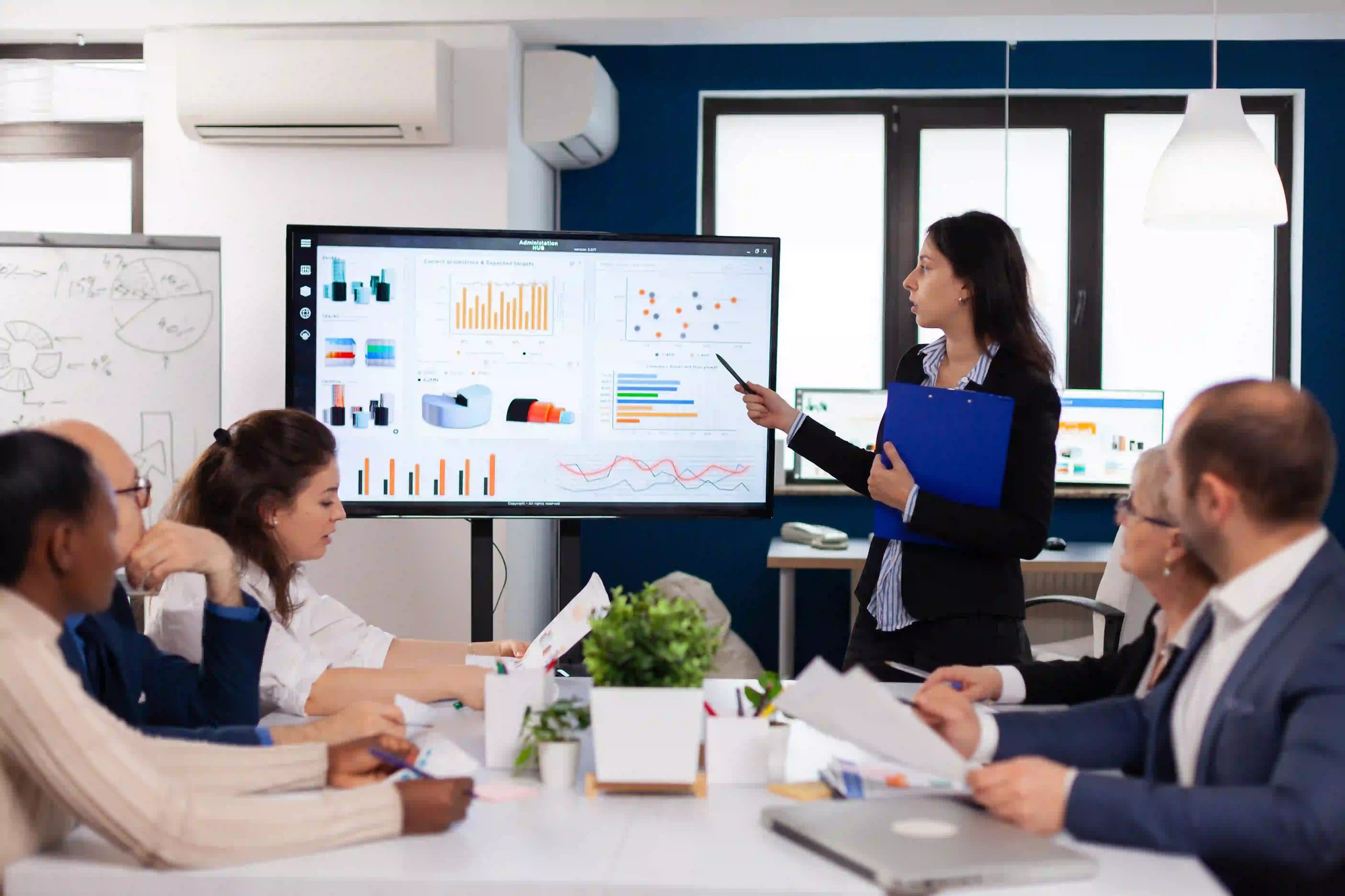 Businesswoman presenting AI data on screen to team in meeting room.